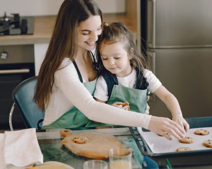 A mother and daughter bonding while baking cookies in a cozy kitchen setting.